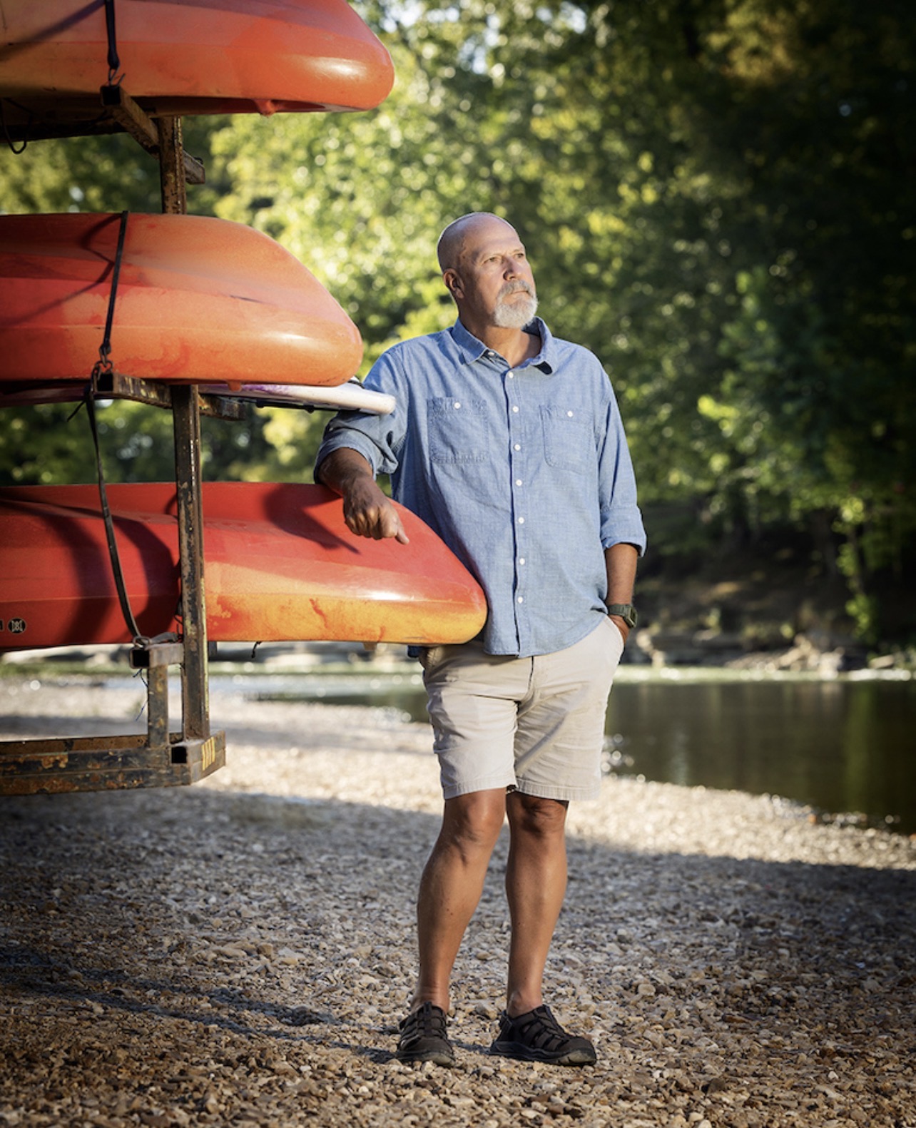 Owner leaning on a rack of kayaks beside the Buffalo River